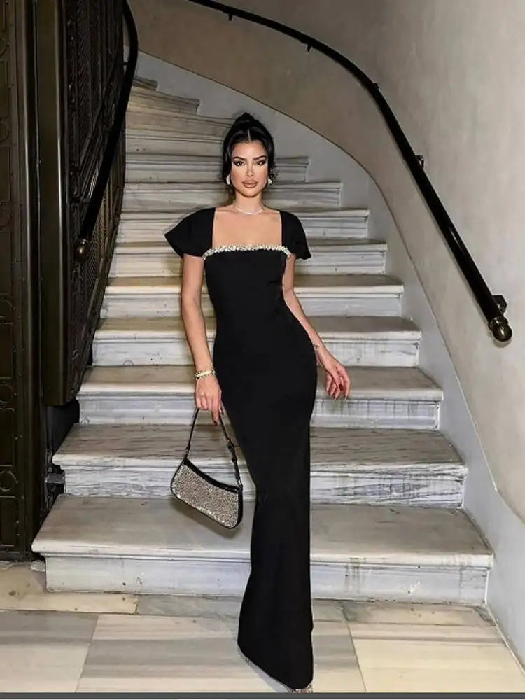 A high-fashion shot of a woman in a flowing silk dress against a sun-drenched architectural background